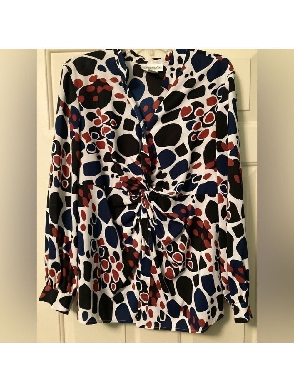 Blouse with a twist front style, has a button front. Navy,Red and black print.